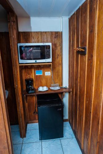 a kitchen with a microwave on a wooden wall at Hospedaje Angeluz in Quesada