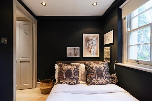 a bedroom with black walls and a bed with pillows at The Myddelton Square - Cosy 1BDR Flat in London