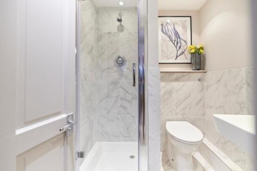 a white bathroom with a shower and a toilet at The Myddelton Square - Cosy 1BDR Flat in London