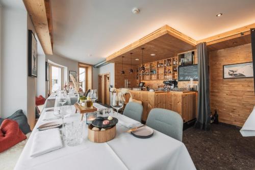um restaurante com mesas e cadeiras brancas e um bar em Leni Mountain Appartements em Sölden