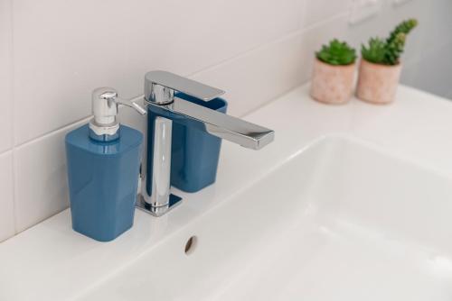 een wastafel in de badkamer met een kraan en een blauwe container bij Tree Apartment BG in Bergamo