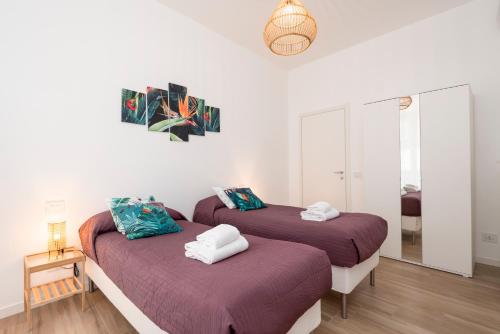 twee bedden in een kamer met witte muren en houten vloeren bij Tree Apartment BG in Bergamo