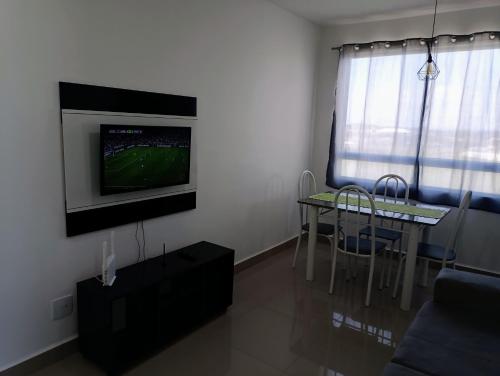 a living room with a table and a television on a wall at Apartamento aconchegante Jd América in Maringá