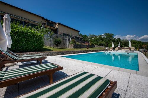 una piscina con 2 sillas de césped y sombrillas en 208 - Appartamento Quercia, Giardino e Piscina - Residence Cherry House, en Carro