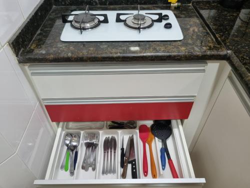 a stove top oven in a kitchen with utensils at Loft Prainha 101, arraial do cabo in Arraial do Cabo