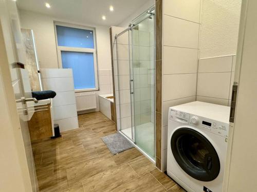 a washing machine in a bathroom with a glass shower at Charmante Altbauwohnung an der Kesselschleuse 1 in Emden