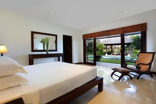 um quarto com uma cama, uma cadeira e uma janela em Jimbaran Luxury 4BR with Butler em Jimbaran