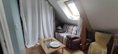 ein kleines Zimmer mit einem Sofa und einem Stuhl in der Unterkunft Chambre Céladon in Changé