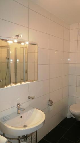 a white bathroom with a sink and a mirror at Landgut Stetter in Schöllnach
