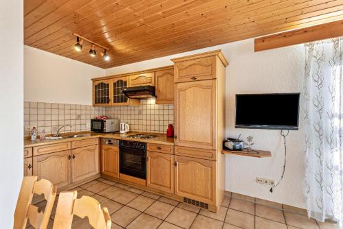 a kitchen with wooden cabinets and a flat screen tv at Ferienhaus Toni in Hohenstein