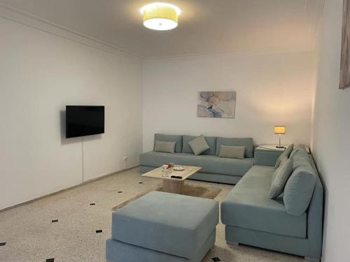 salon z niebieską kanapą i telewizorem w obiekcie Ideal location in the heart of L’hivernage w Marakeszu