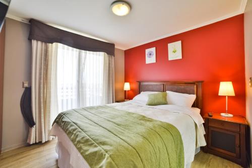 1 dormitorio con cama grande y pared roja en Home Apartments, en Los Ángeles