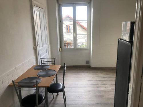 uma cozinha com uma mesa e cadeiras e um frigorífico em STUDIO « LE PARC DES MOULINS » em Troyes