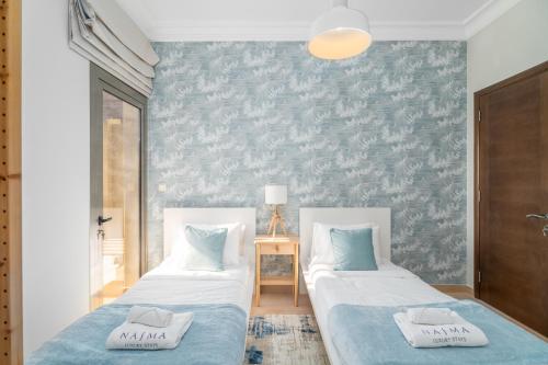 拉斯阿尔卡麦Nasma Luxury Stays - Jaw-dropping 4BR Villa with Calming Golf View的卧室内两张并排的床