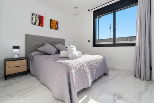 a white bedroom with a bed and a window at La Villa del Roc in Roda de Bará