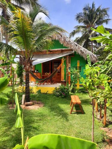 une maison verte et jaune avec des palmiers devant elle dans l'établissement Côco Verde Chalé - Icaraí Kite Village, à Icaraí