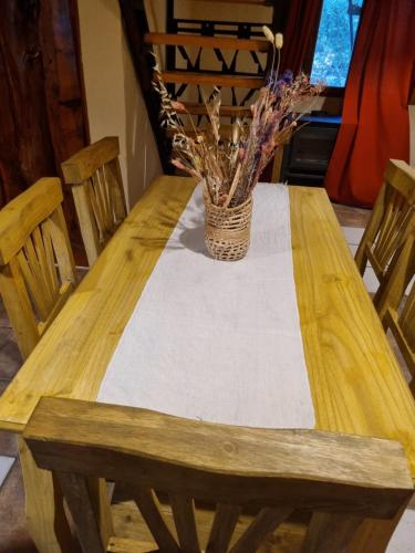 una mesa de madera con un jarrón de flores. en ALMA CALMA en San Marcos Sierras