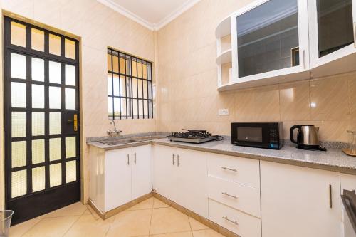 a kitchen with white cabinets and a microwave at OLMOTI SUITES in Arusha
