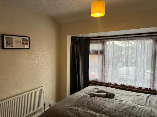 a bed with a stuffed animal on it next to a window at Five Oaks House- Entire 3 Bedroom House for Family & Contractors with up to 5 sleep- NO PARTIES ALLOWED in Willenhall