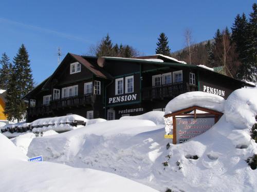 a building covered in snow with a sign in front at Pension Švýcarský dům in Trutnov