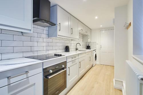 a kitchen with white cabinets and a sink at Host & Stay - Penny Farthing Cottage in Whitby