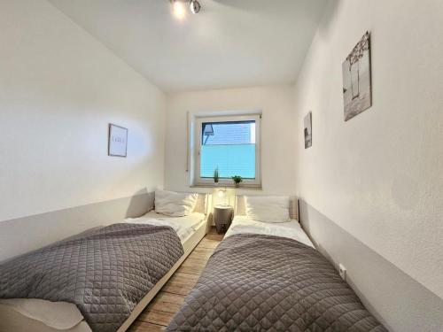 two beds in a room with a window at Mienhus Apartments Ferienwohnung Fiete in Norden