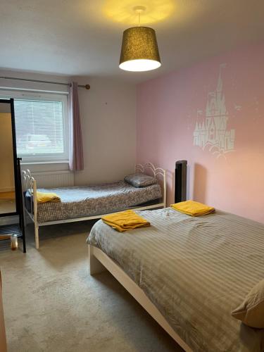 a bedroom with two beds and a window at Spacious Apartment near Heathrow with Allocated Parking in Uxbridge