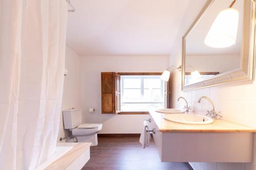 ein Badezimmer mit einem Waschbecken, einem WC und einem Spiegel in der Unterkunft Camiño Ancho casa rural in Pobra do Caramiñal