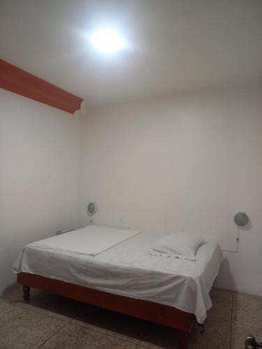 1 cama en una habitación con una luz en la pared en Hostal Continental en Manta