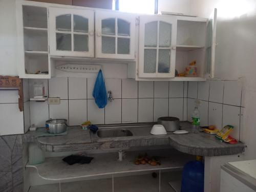 una cocina con armarios blancos y fregadero en Hostal Continental en Manta