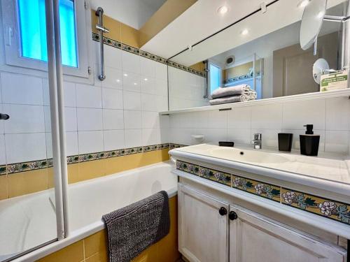 uma casa de banho com um lavatório, uma banheira e um espelho. em Les Restanques 4027 vue mer grande terrasse em Grimaud