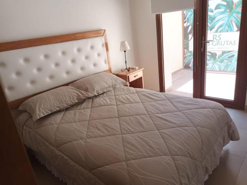 1 dormitorio con 1 cama con edredón blanco grande en RS Las Grutas, en Las Grutas