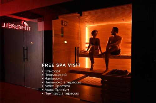 a man and a woman sitting on a bed in a sauna at Il Decameron Luxury Design Hotel in Odesa