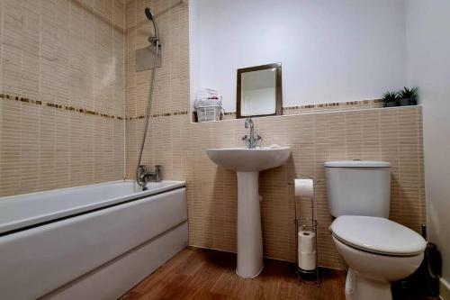 a bathroom with a sink and a toilet and a bath tub at A modern and spacious home. in Luton