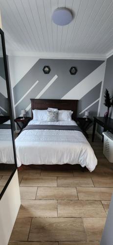 a bedroom with a white bed with a wooden floor at 20 Fisant Cottage in Cape Town