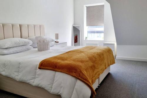 a bedroom with a large bed with a blanket on it at A modern and spacious home. in Luton