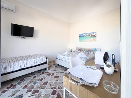 a room with two beds and a flat screen tv at Ponente & Maestro Rooms in Favignana