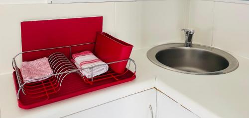 a red basket with towels next to a sink at Studio@PlaneSt in Jeffreys Bay