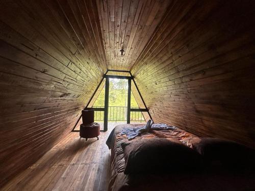 a bedroom with a large window in a wooden wall at Bungalows Tenorio Montand Lodge in San Rafael