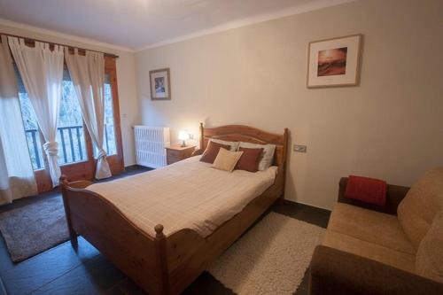 1 dormitorio con cama de madera y sofá en XALET CARLEMANY (Casa entera /hab.), en Erts