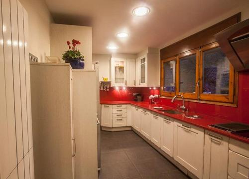 cocina con paredes rojas y nevera blanca en XALET CARLEMANY (Casa entera /hab.), en Erts
