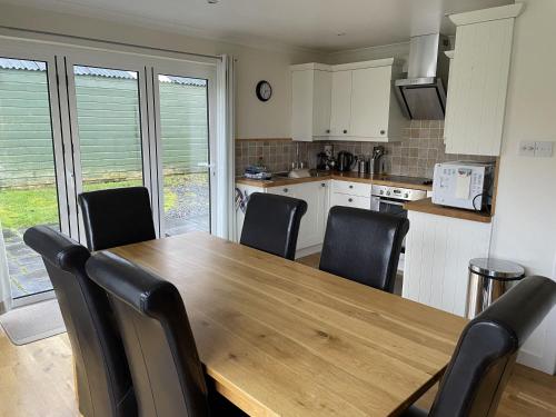 a kitchen with a wooden table and black chairs at The Cottage, overlooking Loch Fyne in Cairndow