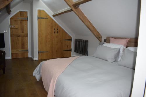 a bedroom with a white bed and a wooden door at Dairy in the Black Mountains in Abergavenny