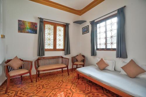 Villa Seafront Goa في أنجونا: غرفة بسرير وكراسي ونوافذ