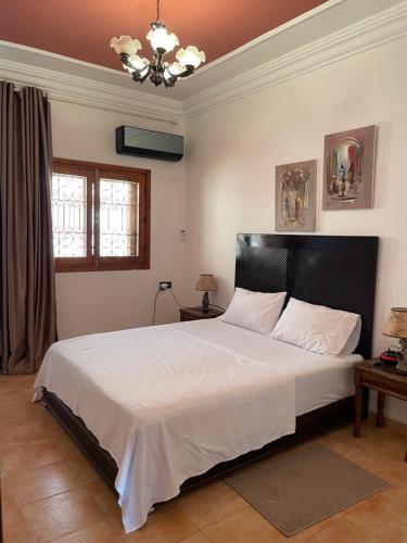 a bedroom with a large white bed with a black headboard at Dar El fayda in Oulad Raho