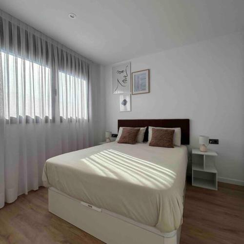 Un dormitorio blanco con una cama grande y una ventana en Estrénalo a minutos de BCN, en Sant Feliu de Llobregat