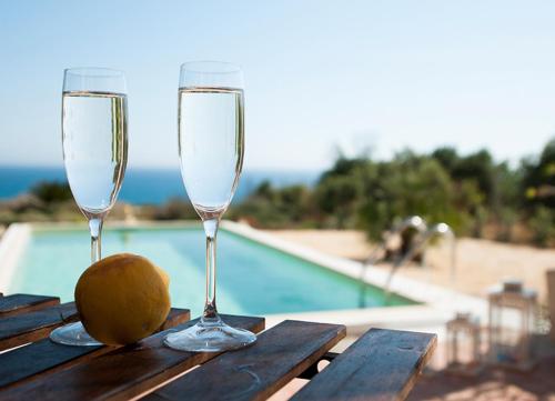 two glasses of champagne and a kiwi on a table next to a pool at Jabia Beach House in Marinella di Selinunte