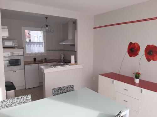 uma cozinha com armários brancos e flores vermelhas na parede em Gîte Cap Goéland - Maison chaleureuse au cœur du site des 2 Caps em Audinghen