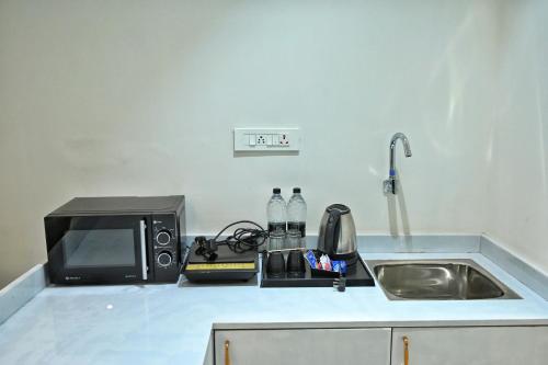 a kitchen counter with a microwave and a sink at The One Hotel Nashik in Nashik