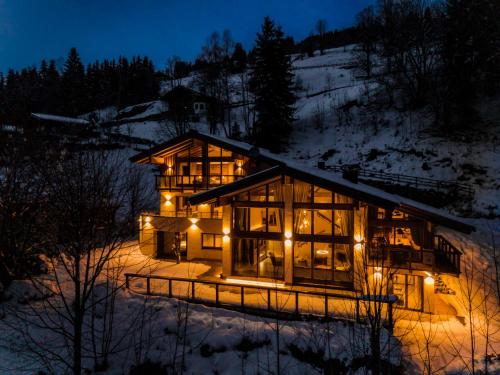 a large building with lights in the snow at night at Chalet VIE in Viehhofen